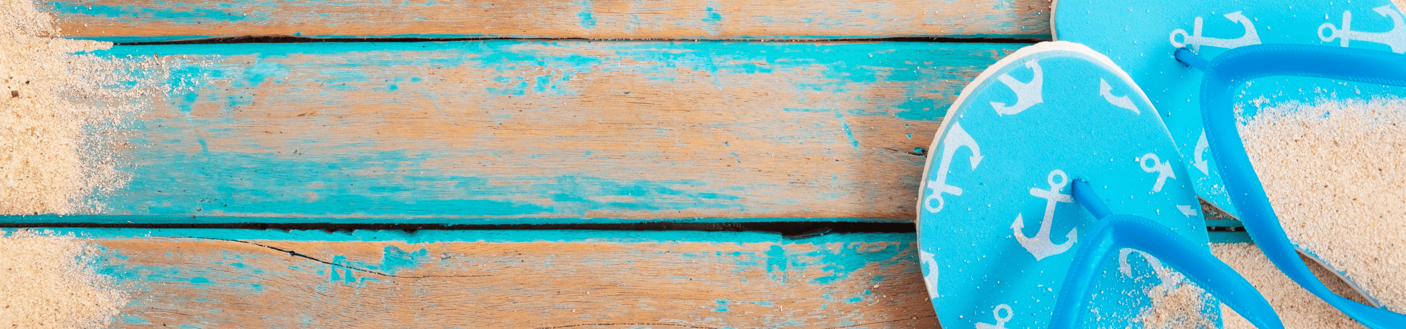 blue flip flops with sand on them sitting blue and tan wood.