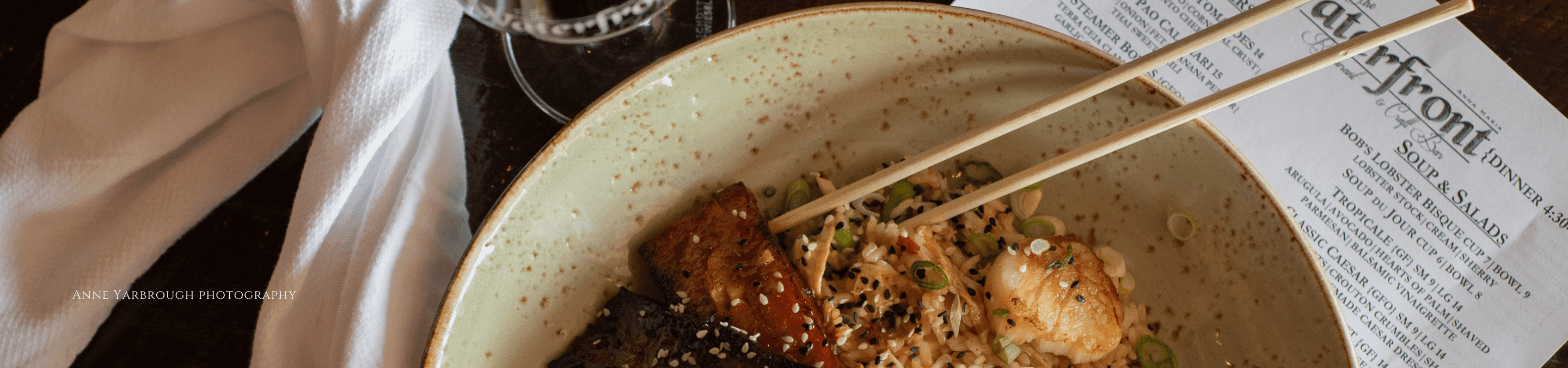 Bowl of seafood with Chopsticks and a menu from The Waterfront Restaurant in Anna Maria Florida